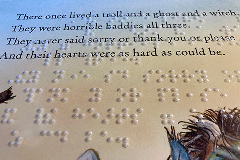 Close up image of clear plastic sheet with embossed braille that matches the original page of text and illustration from The Baddies seen through it.