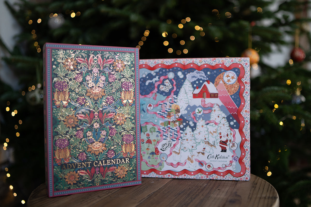 A William Morris and a Cath Kidston beauty Advent calendar on a small table in front of a decorated Christmas tree