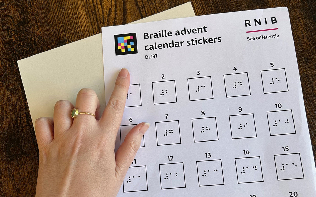 A person pointing to the NaviLens code on RNIB's braille advent calendar stickers.