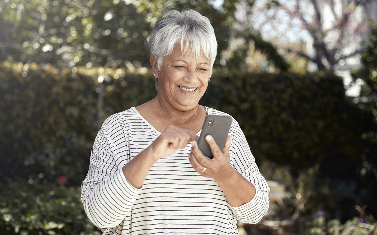 A smiling woman with short, white hair smiles while using her Synapptic smartphone