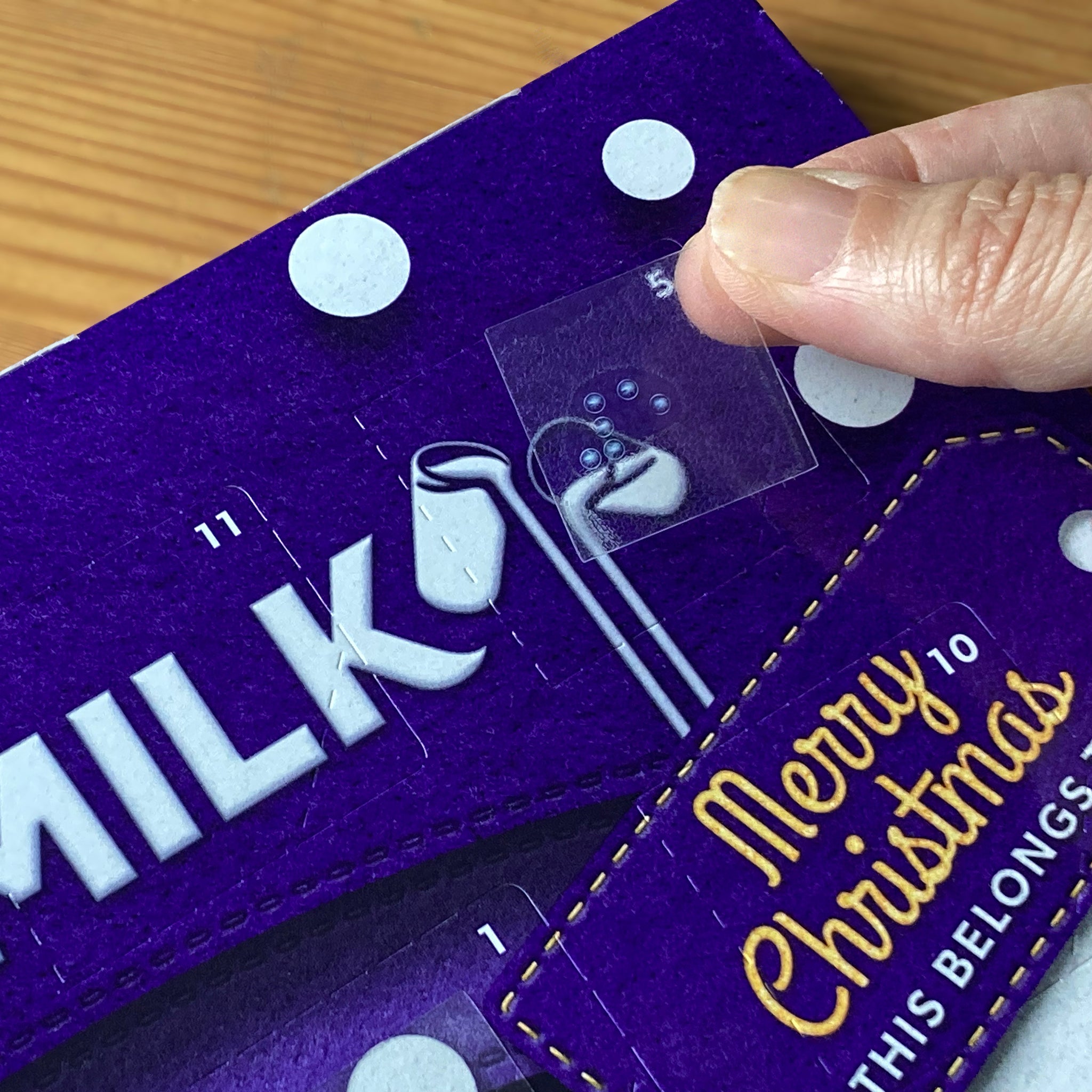 Someone applying a braille number sticker to an Advent calendar