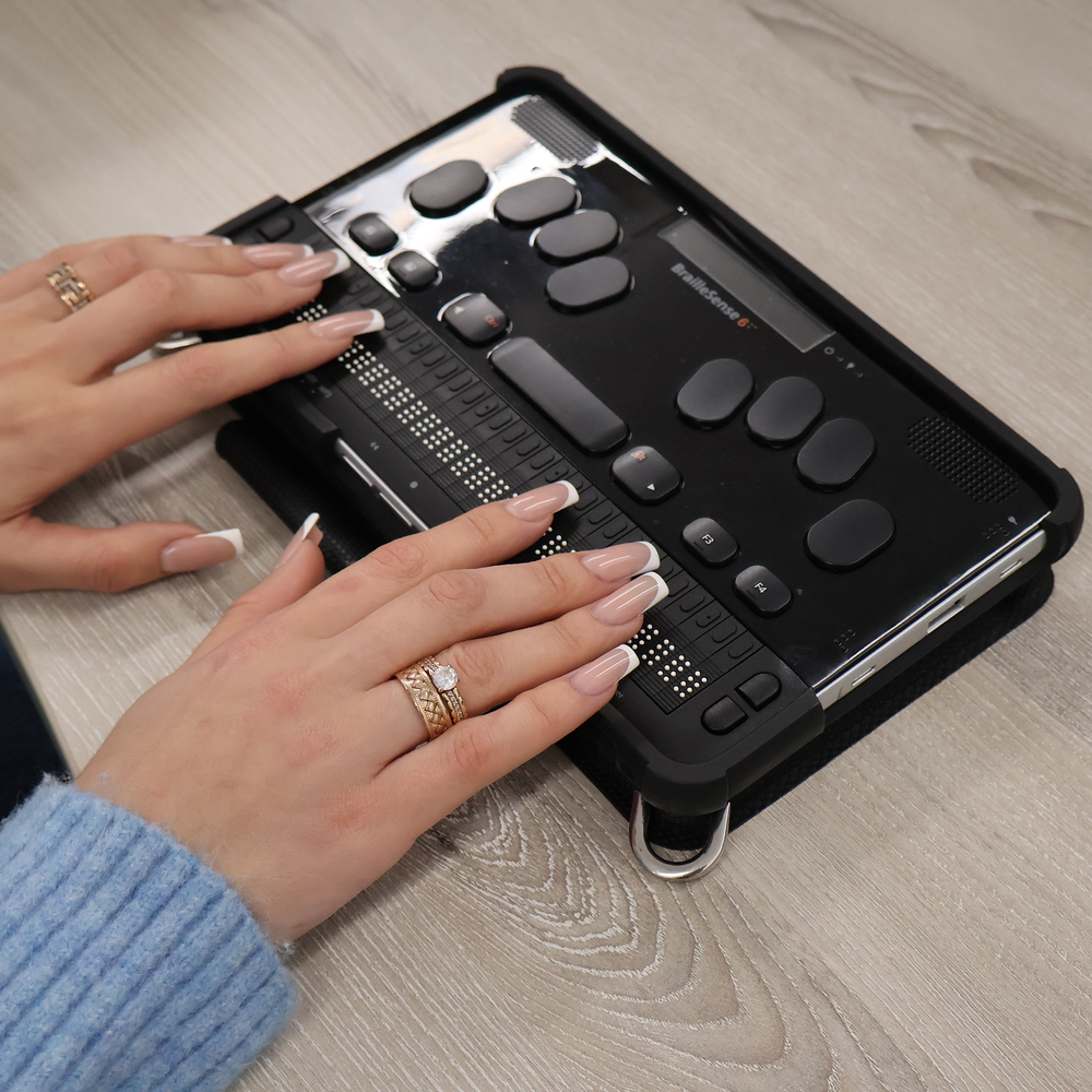 A person using the BrailleSense 6 notetaker at a desk