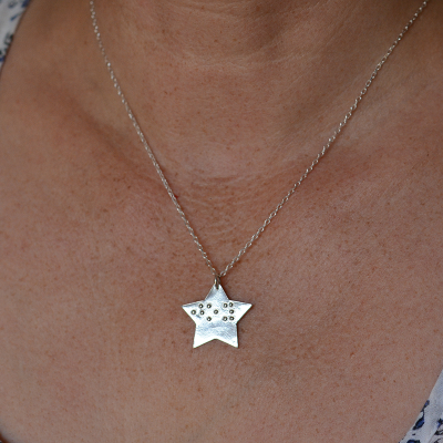 Star-shaped silver pendant being worn