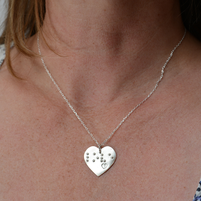 Heart-shaped silver pendant being worn