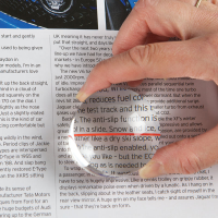 Close-up of person using magnifier on a page of text