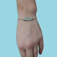 Adjustable silver bracelet with ‘love’ in braille being worn