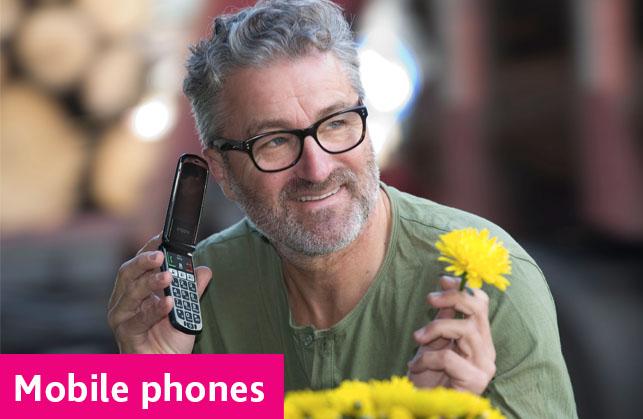 A white man holding a mobile phone in one hand and a yellow flower in the other