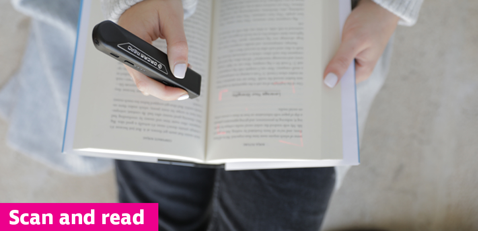 Overhead view of a person using a handheld scanning device to read a book