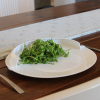 White plate surround being used on a plate to hold salad in place