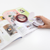 Magnifier opened to show magnifying lens on a magazine