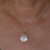 Disc-shaped silver pendant being worn