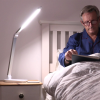 Man reading in bed using the desk lamp