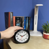 A hand activating the clock on a bedside table