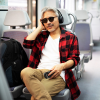 Lifestyle image shows man on a train holding product with headphones in