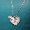 Back view of Heart-shaped silver necklace with ‘mum’ in braille and charm