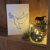 Inclusive dove Christmas card on a shelf with Christmas decorations