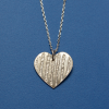 Back view of heart-shaped silver pendant against a white background