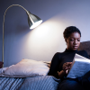 A young black woman on a sofa reading under the light