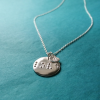 Front view of Disc-shaped silver necklace with ‘love’ in braille and charm