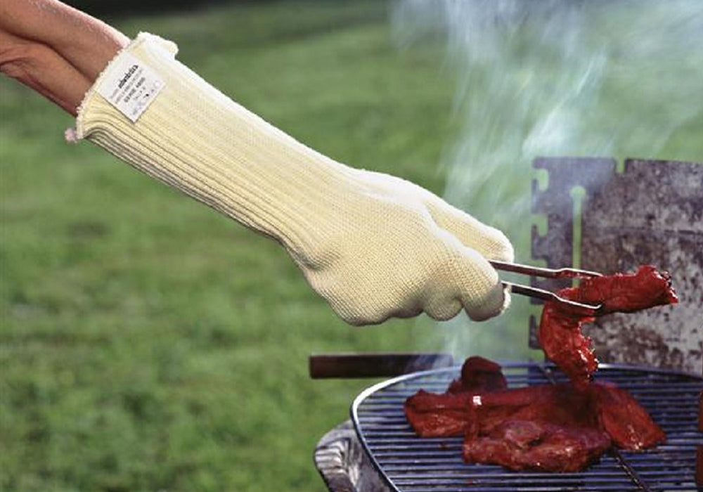 A person wearing long five-fingered hear-resistant oven gloves while turning meat on a barbecue with tongs