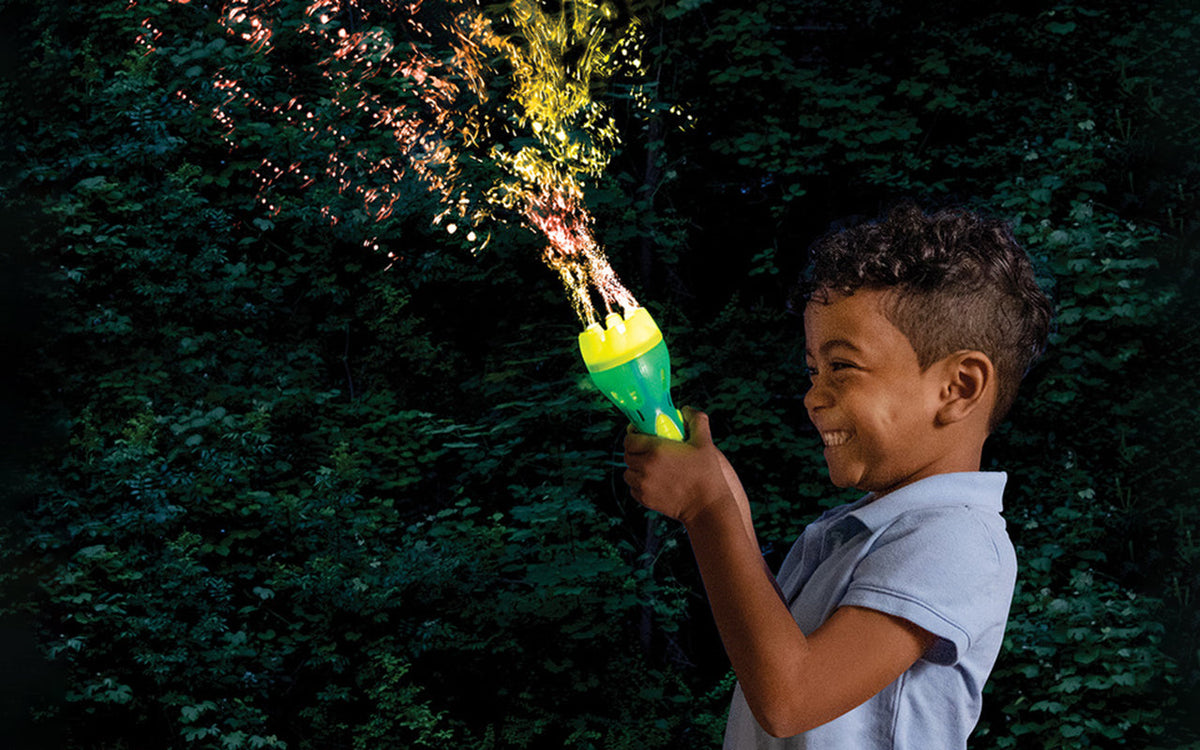 A young boy beams as he creates a stream of coloured bubbles with a light-up bubble torch