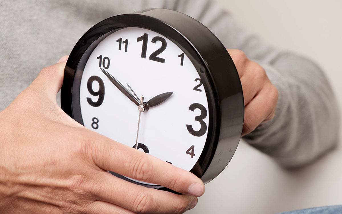 A person adjusting the time on a clock with large, high contrast numbers.