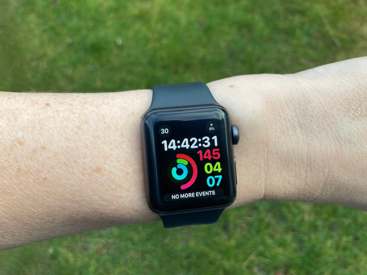 A white person's wrist wearing an Apple watch which displaying activity rings