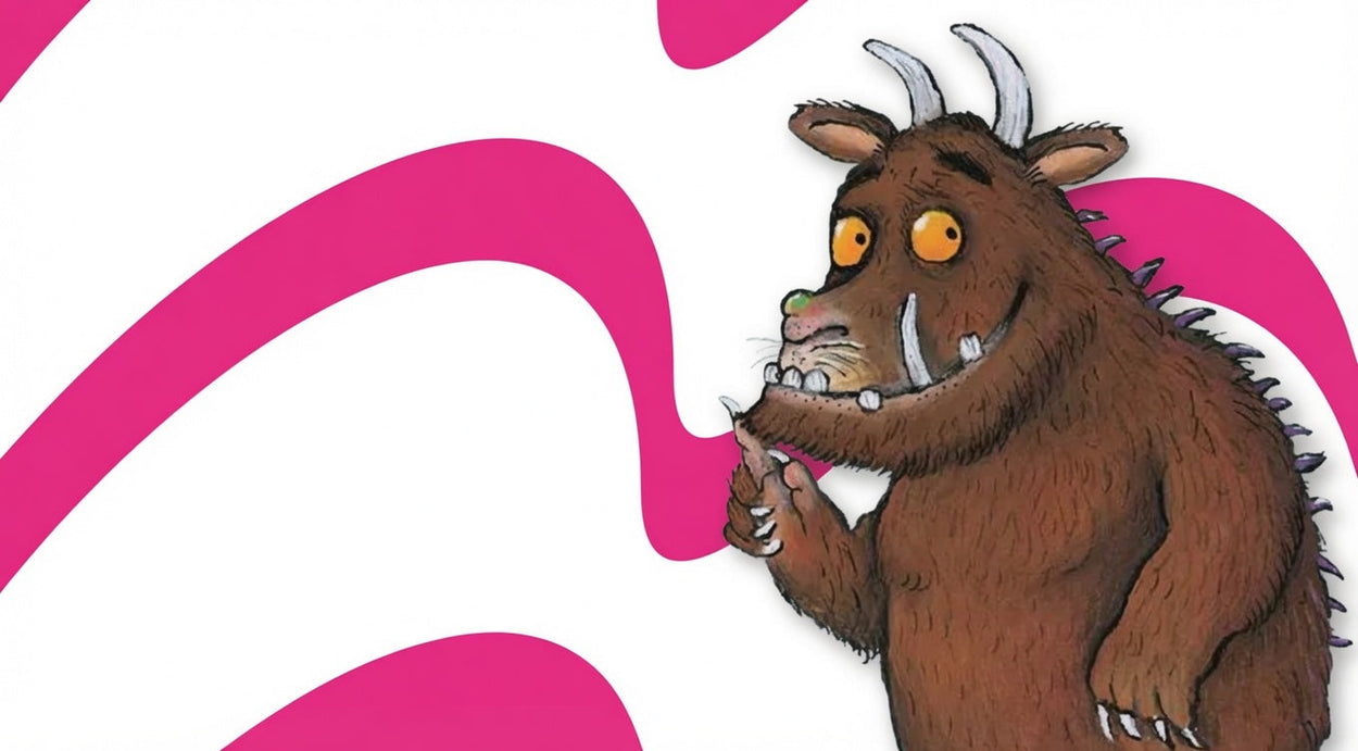 The Gruffalo, a brown furry monster with large orange eyes, curved horns, tusks, and spines, pointing at its open mouth with one claw. The character is shown against a white background with bold pink curved swirls.
