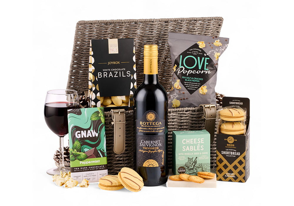 Wicker hamper with contents including a bottle of wine and sweet and savoury treats