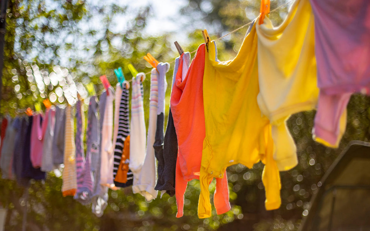 Colourful baby clothes pegged on a washing line in a garden on a sunny day