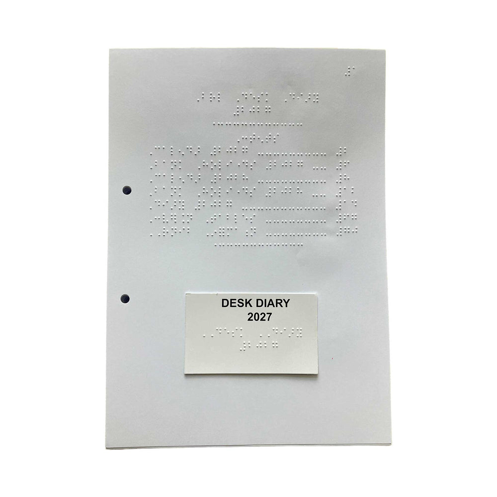 A white desk diary with embossed Braille text, featuring two pre-drilled holes on the left margin and a small white label at the bottom that reads 'DESK DIARY 2027' in black text.
