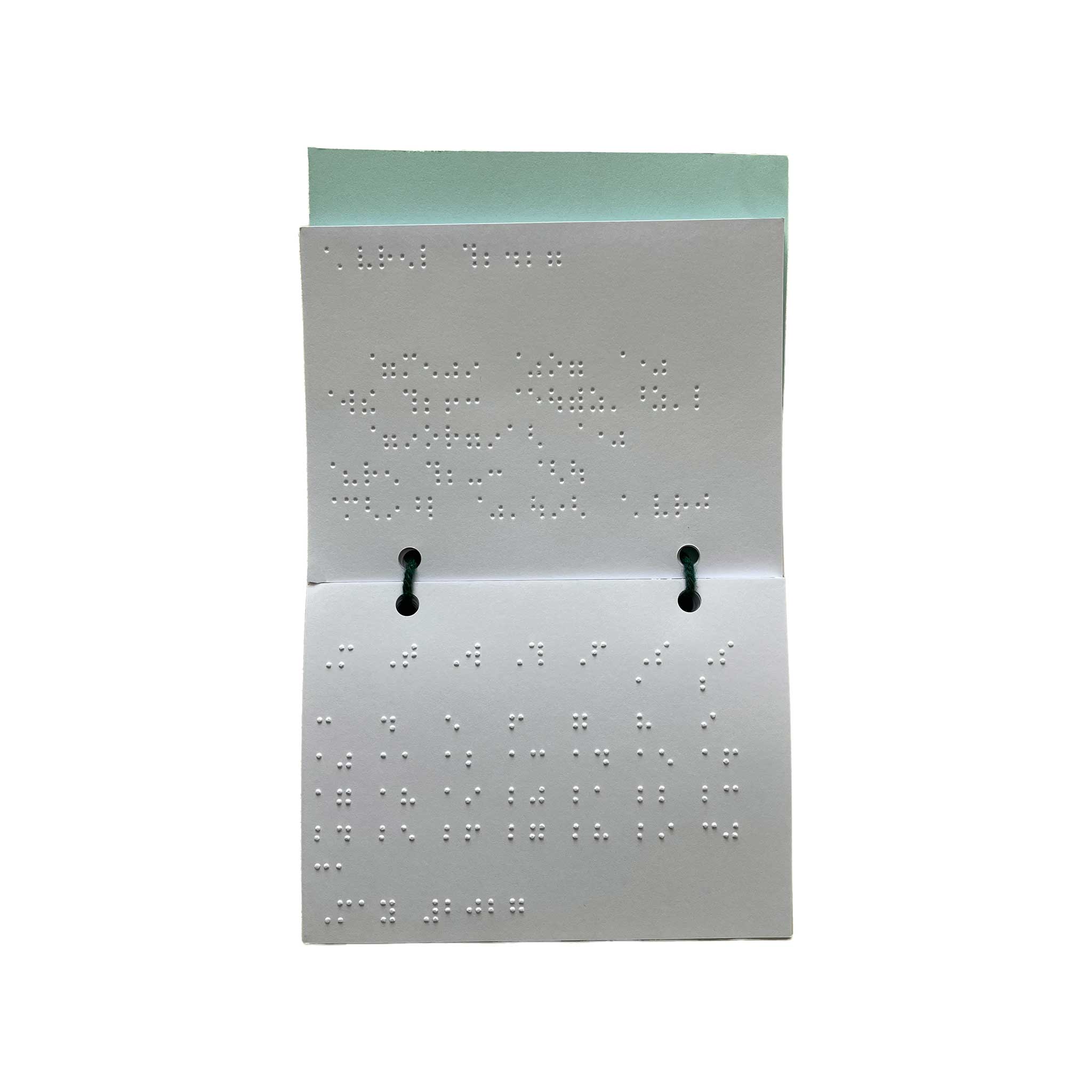 Braille pocket date calendar open with two black binder clips, shown against a plain white background.