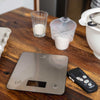 Digital kitchen scale on a wooden table with measuring cups and Ikonn control in the background.