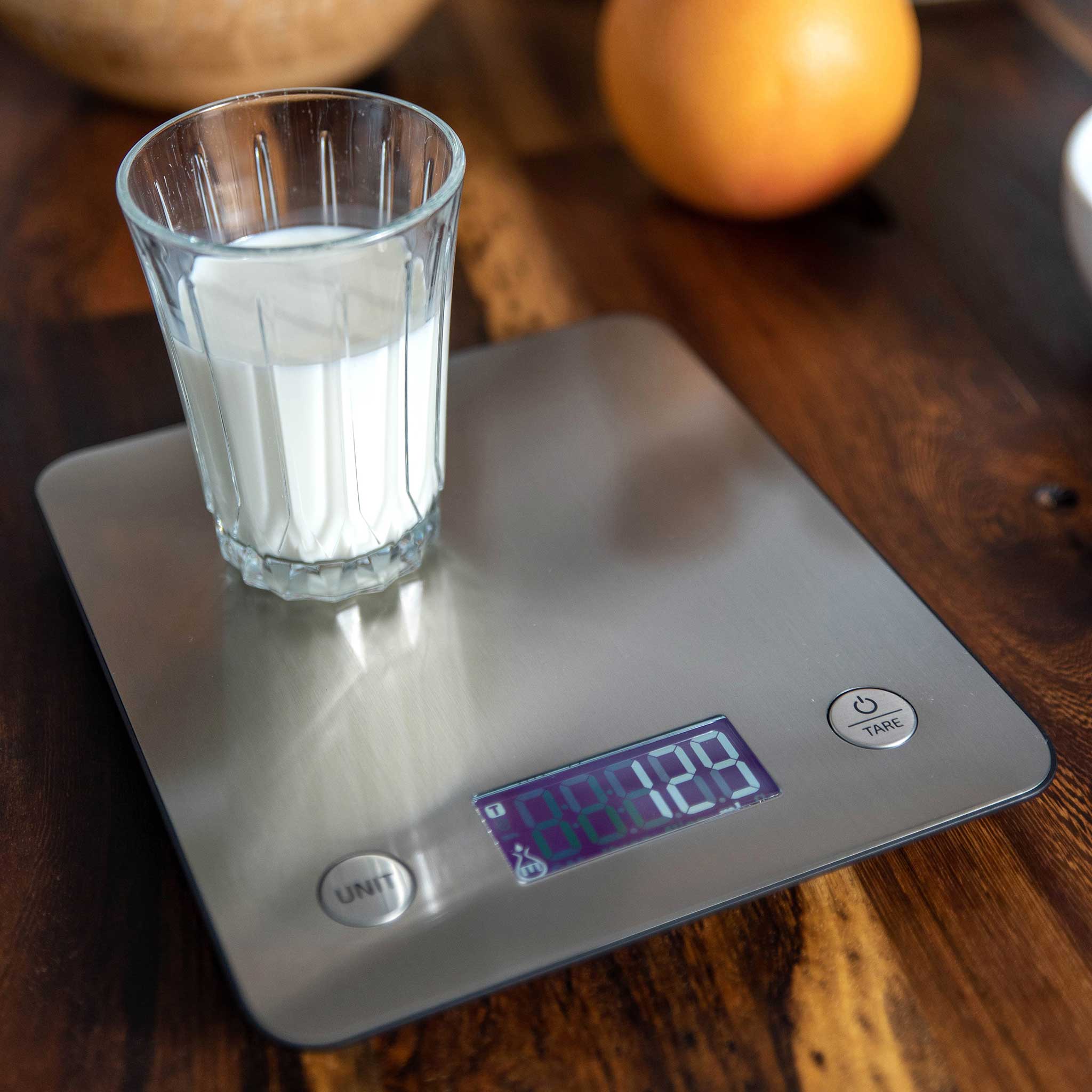 Ikonn kitchen scale with a glass of milk on a wooden surface