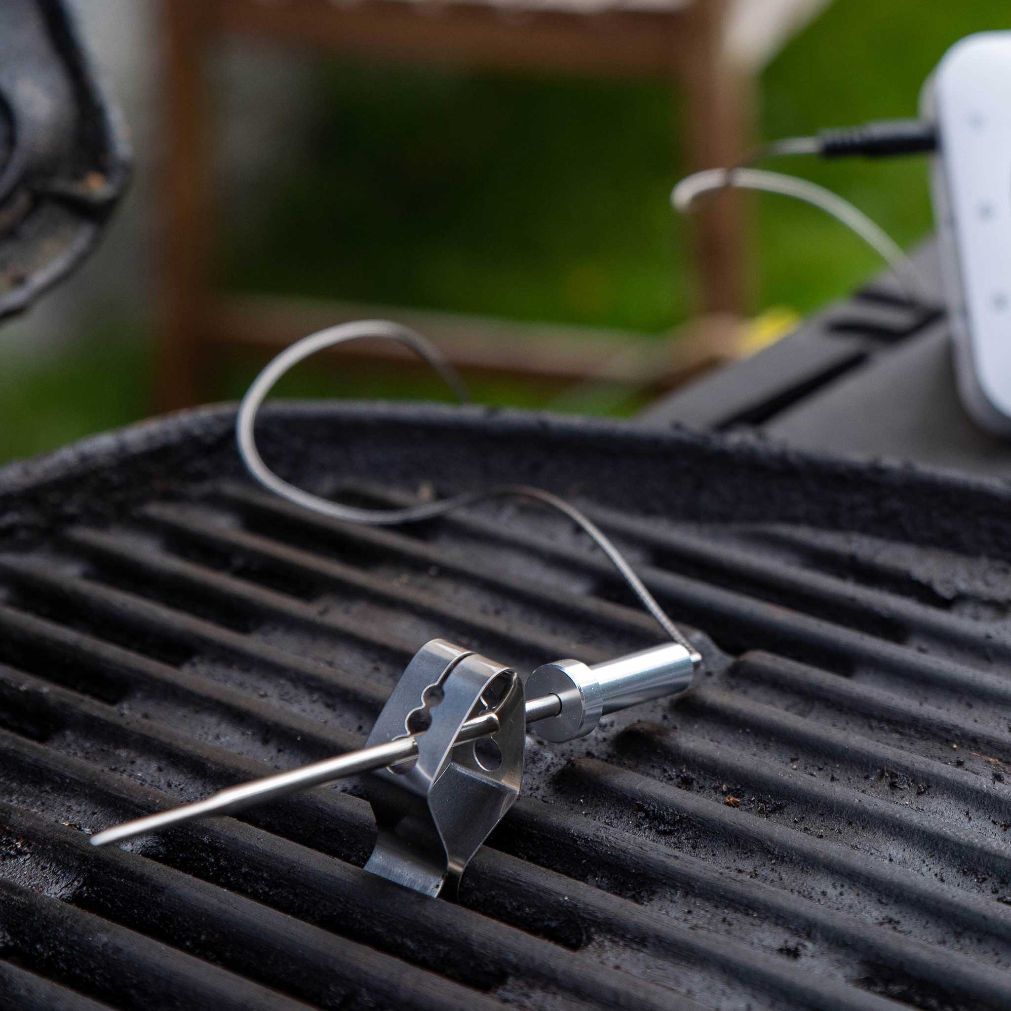 Thermometer probe on a grill with a blurred outdoor background