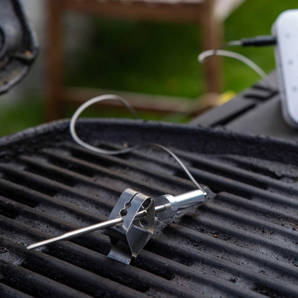 Thermometer probe on a grill with a blurred outdoor background
