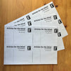 Three A4 sheets of Articles for the blind labels fanned on a wooden surface