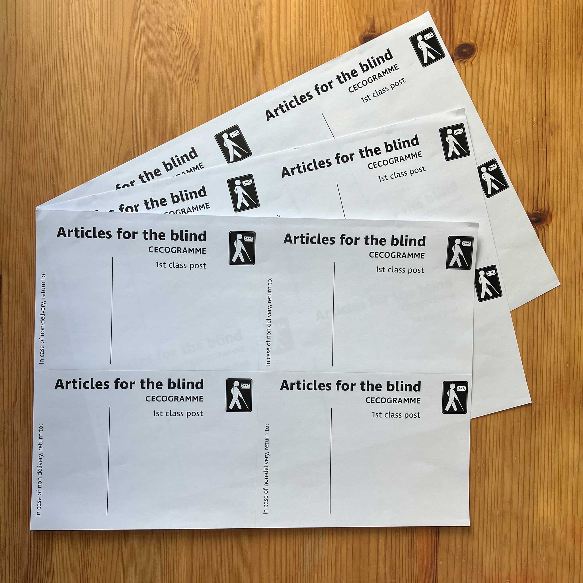 Three A4 sheets of Articles for the blind labels fanned on a wooden surface