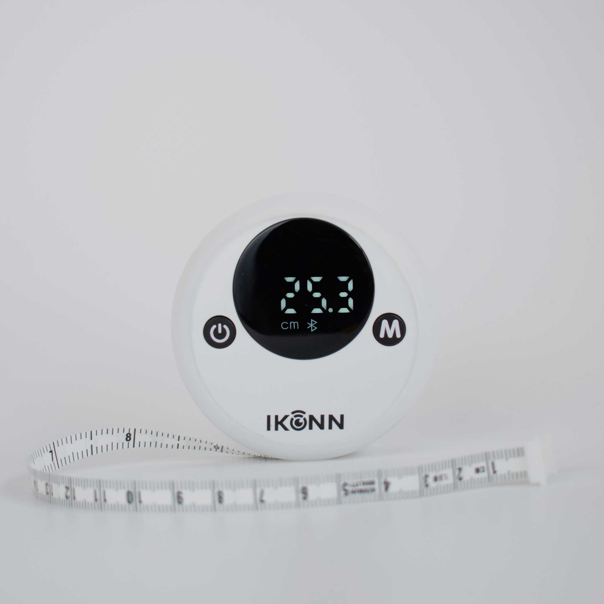 White Ikonn tape measure with contrasting back on and off button. Has a visual display showing the 25.3cm with part of the tape measure showing.