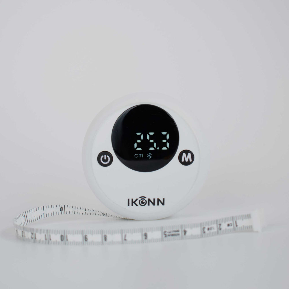 White Ikonn tape measure with contrasting back on and off button. Has a visual display showing the 25.3cm with part of the tape measure showing.