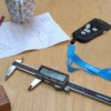 Digital caliper on a wooden surface with a lanyard and paper in the background