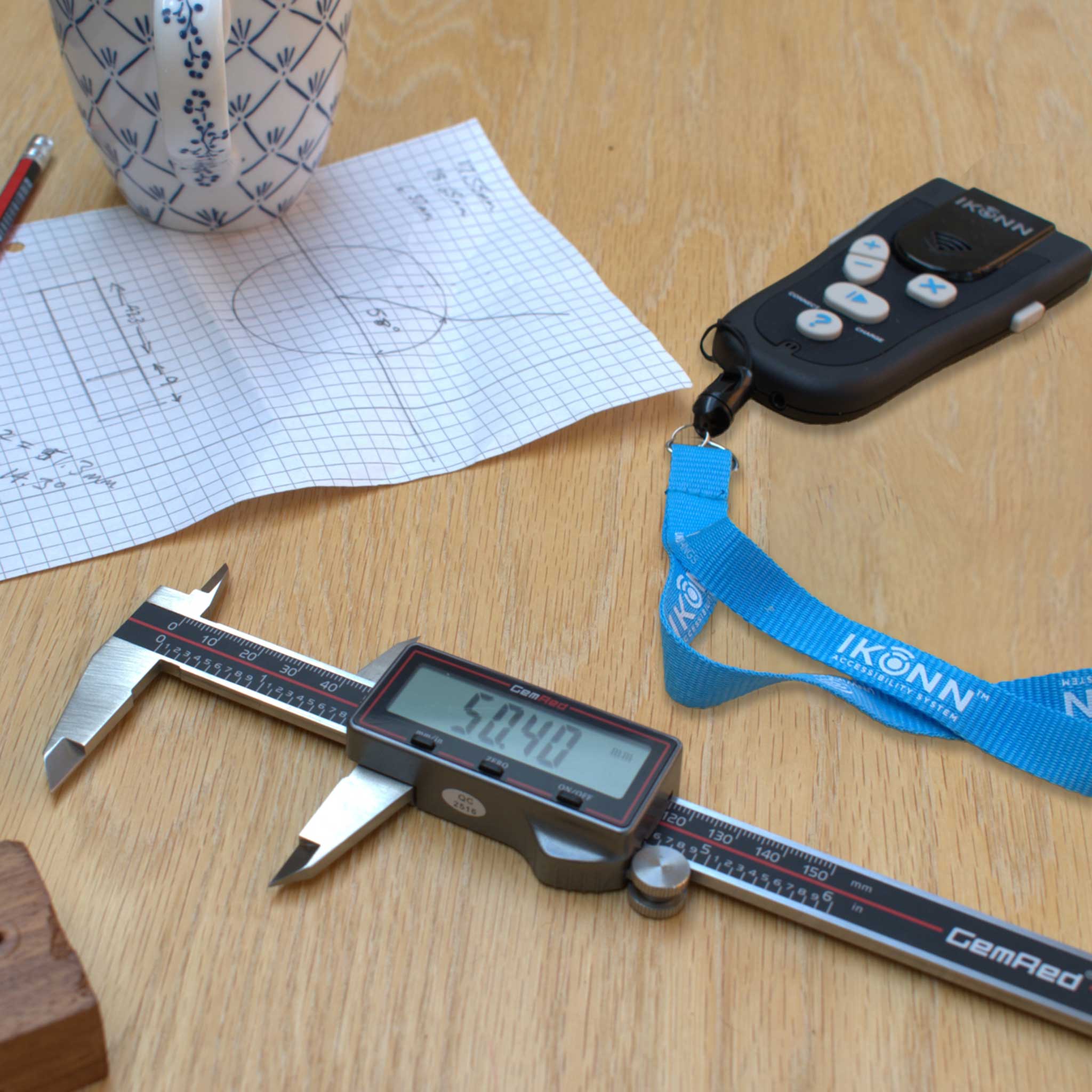 Digital caliper on a wooden surface with a lanyard and paper in the background