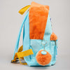 A light blue and orange plush backpack with yellow straps, shown from the side against a neutral gray background.