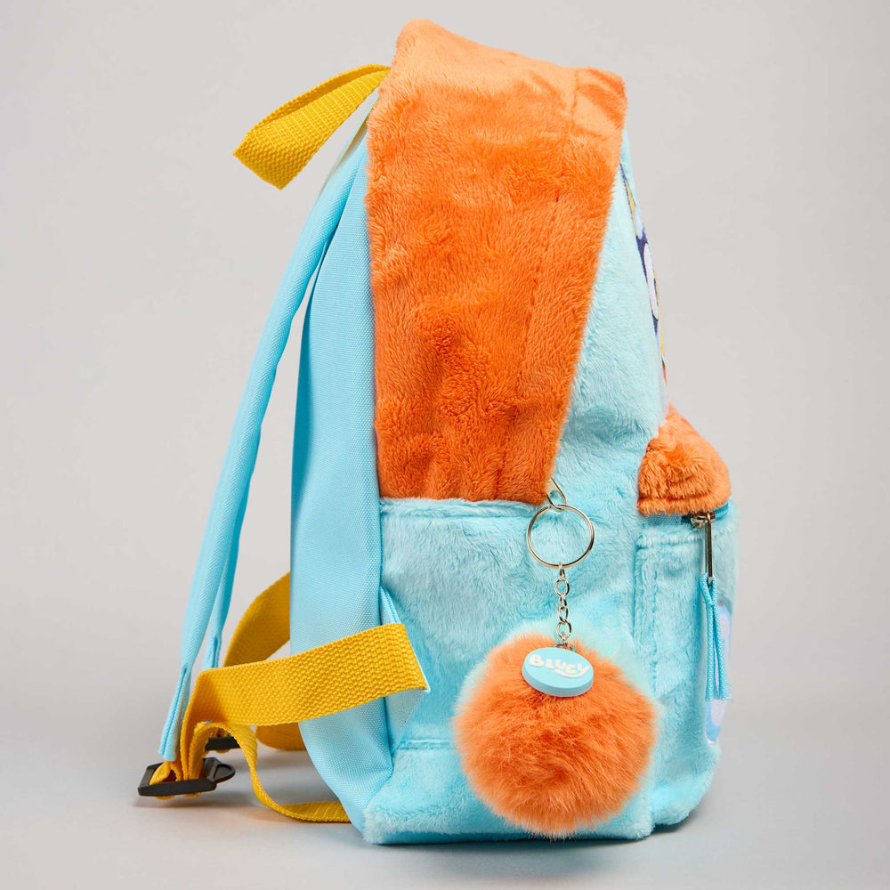 A light blue and orange plush backpack with yellow straps, shown from the side against a neutral gray background.