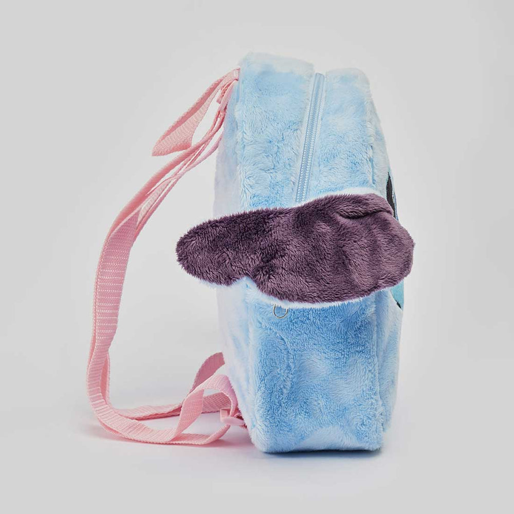 A plush zippered pouch or small backpack in light blue with a purple fuzzy flap detail and pink shoulder strap, photographed on a clean light gray background.