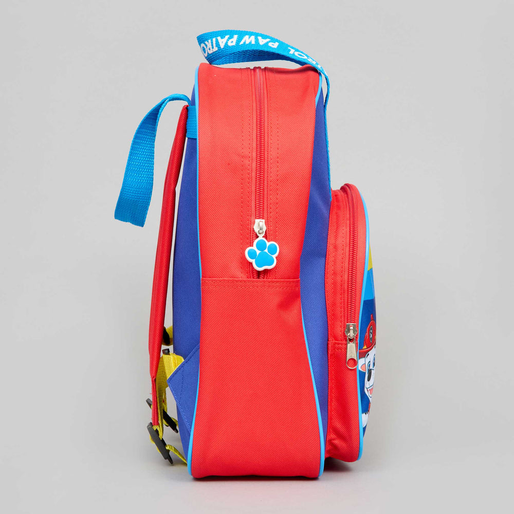 A red and blue Paw Patrol themed backpack shown from the side, featuring a blue paw print zipper pull and a top carrying handle with Paw Patrol branding, set against a neutral gray background.