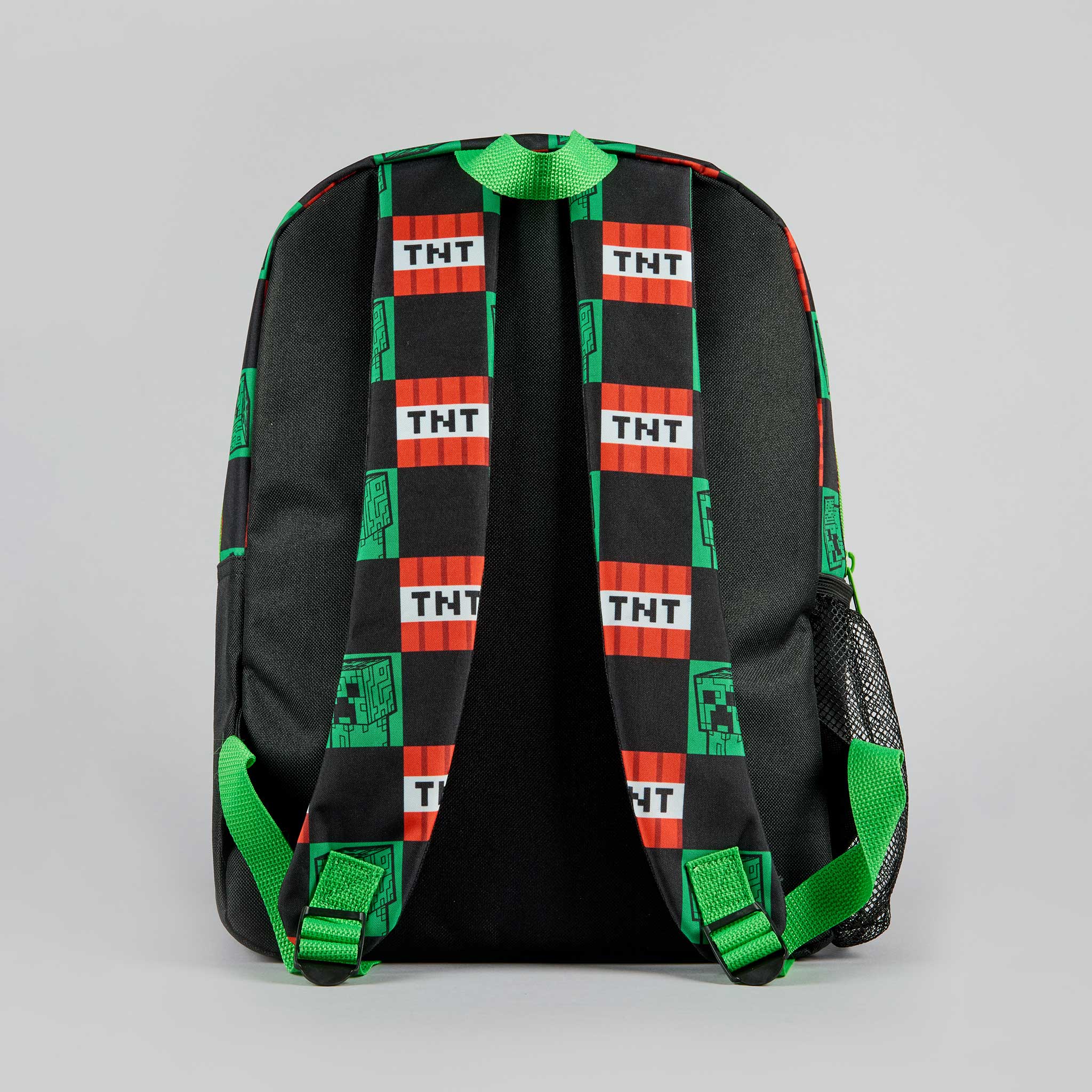 A black backpack featuring a green and red checkered TNT block pattern, shown from the back against a neutral gray background.