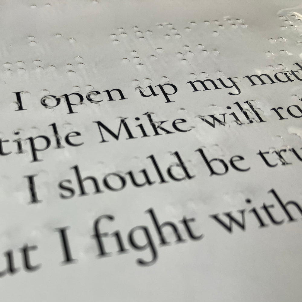 Close-up of clear braille sheet over original text in the book.