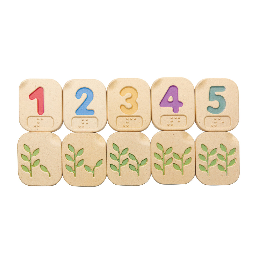 Braille number tiles in two neat rows. Top row shows one to five on the colourful number side, bottom row shows the back of six to ten with plants with the appropriate number of leaves.