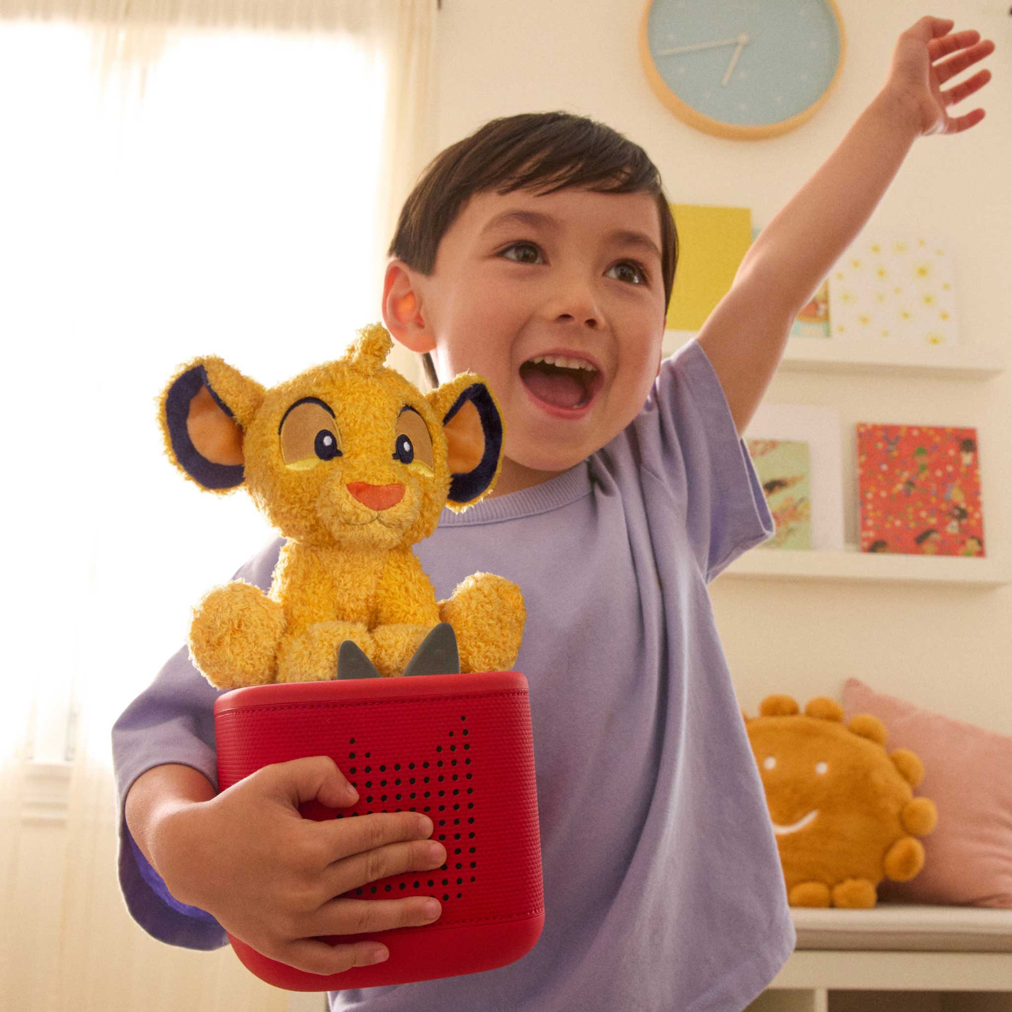 Child holding a plush toy in a red container with a room in the background